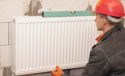 Technician installing central heating radiators