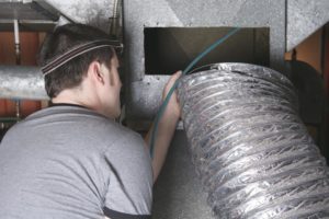 Worker fixing a big silver pipe