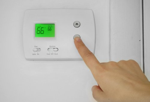 Person adjusting a thermostat in Annapolis, MD