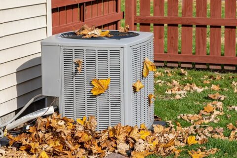 hvac unit sitting in fall leaves needing maintenance