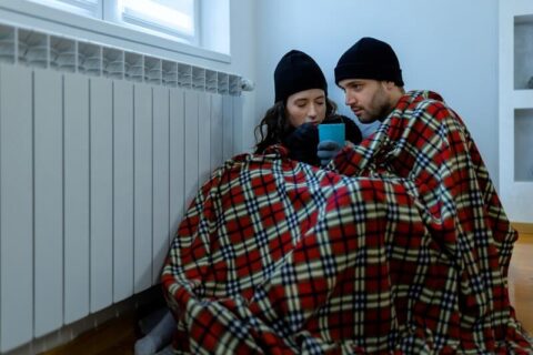 Couple wearing a beanie and blankets because their furnace doesn't work