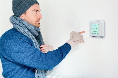 man who is cold adjusting thermostat to warm up