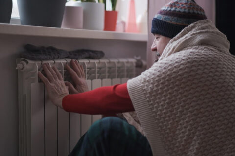 woman in need of emergency hvac repairs trying to warm up